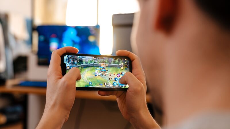 A person holds a smartphone with a mobile game open on the screen
