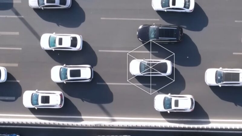 Aerial view of cars on a motorway with one white vehicle marked by a digital network frame
