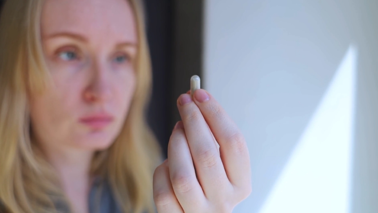Woman holds a magnesium capsule in her hand