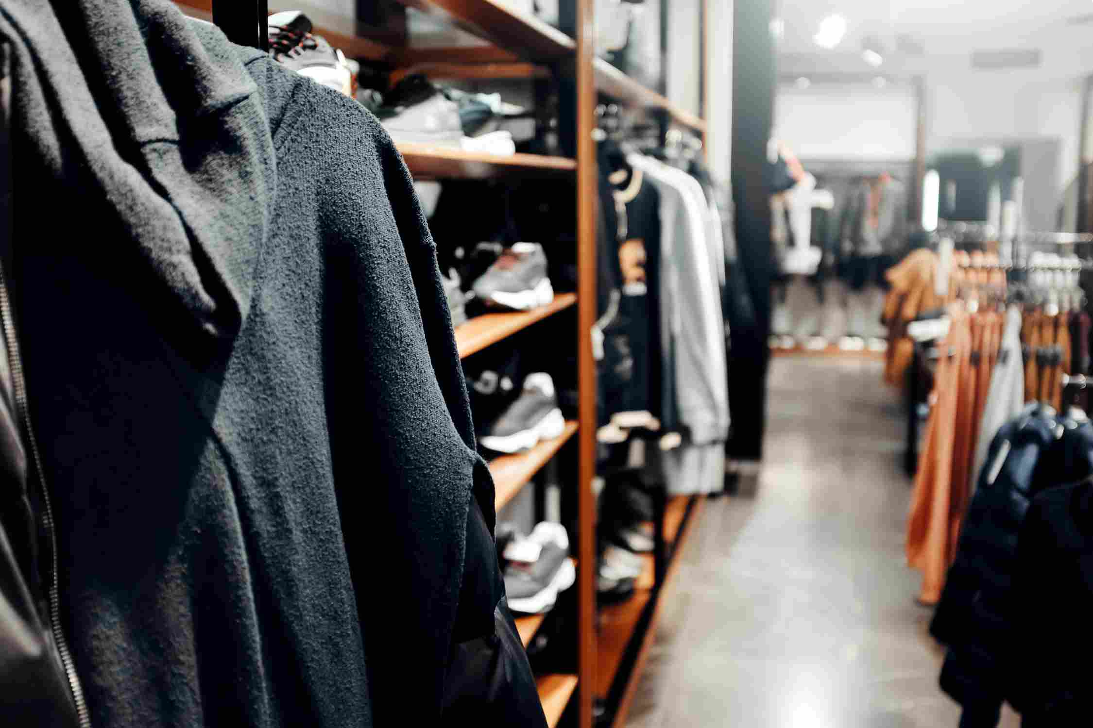 Close-up of dark clothing displayed on racks inside a modern fashion retail store.